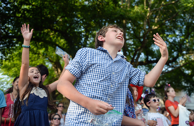 Children in the crowd beg for candy as cars in the parade drive by.