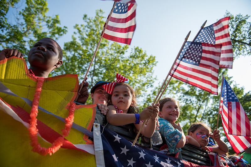 Kids smile and wave flags atop a float in the parade.