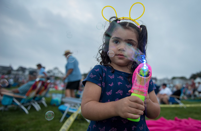 Amera Mello, 3, plays with a bubble gun while waiting for the band to come on.