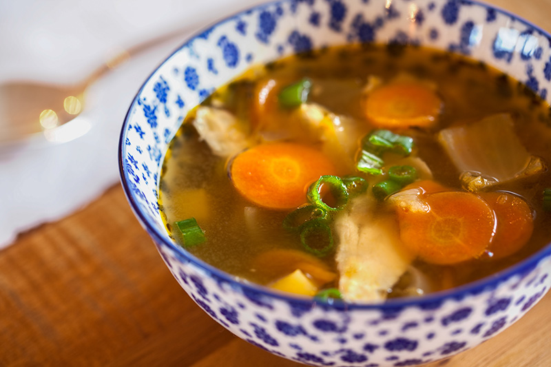Chicken soup in a white and blue bowl