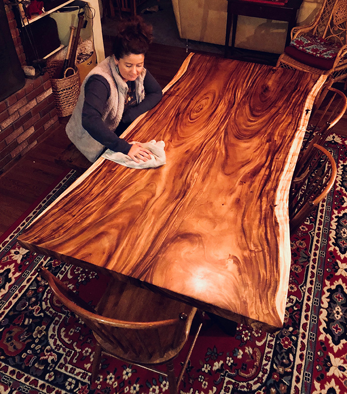 Liz Ragone puts the finishing touches on a wood table.