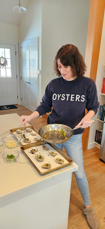 Julia Blanter placing butter, herbs, and garlic on the oysters.