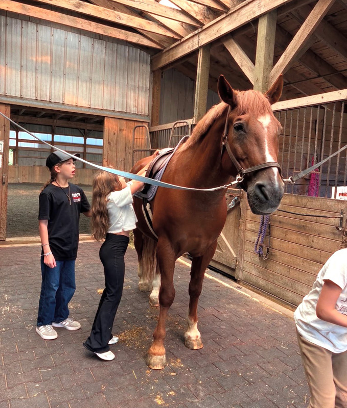 Kids learn to tack up horses for riding.