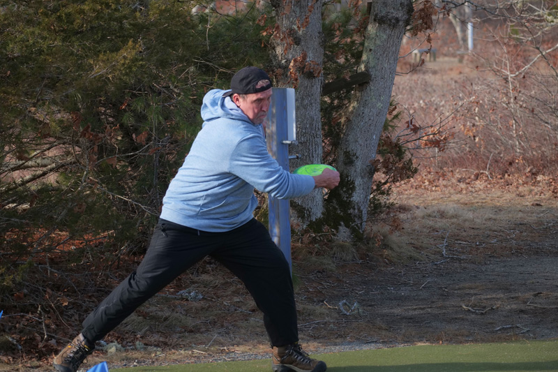 Disc golfer throws from the tee box.